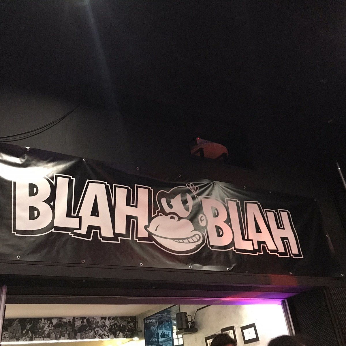 Insegna del Blah Blah appesa sopra l'ingresso: la scritta BLAH BLAH in grandi lettere bianche con una testa di scimmia in mezzo